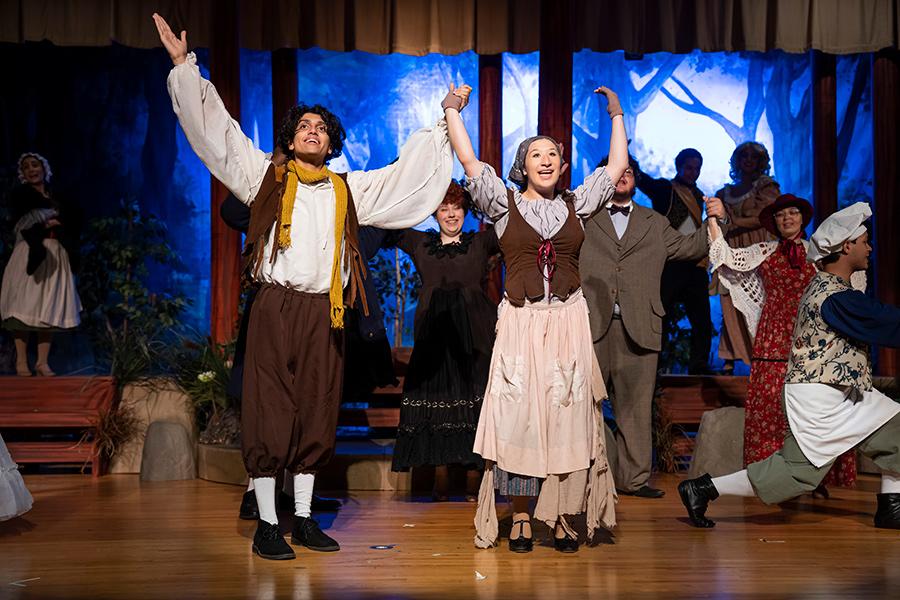 Two Iona Players raise their arms in a production of Into the Woods.