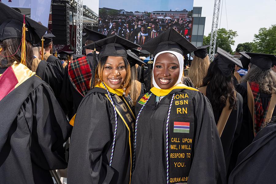 Two 2023 graduates face the camera and smile.