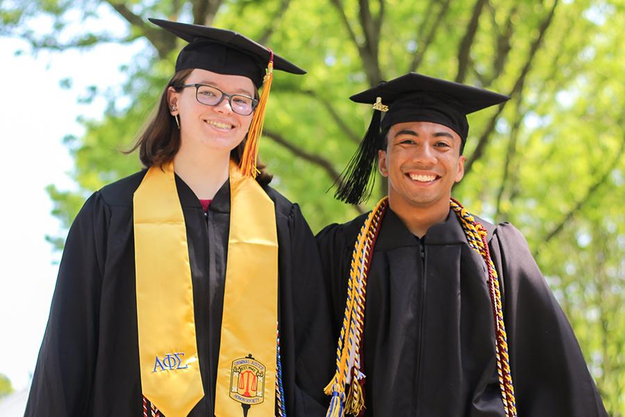 Two 2023 Iona graduates in regalia smile.