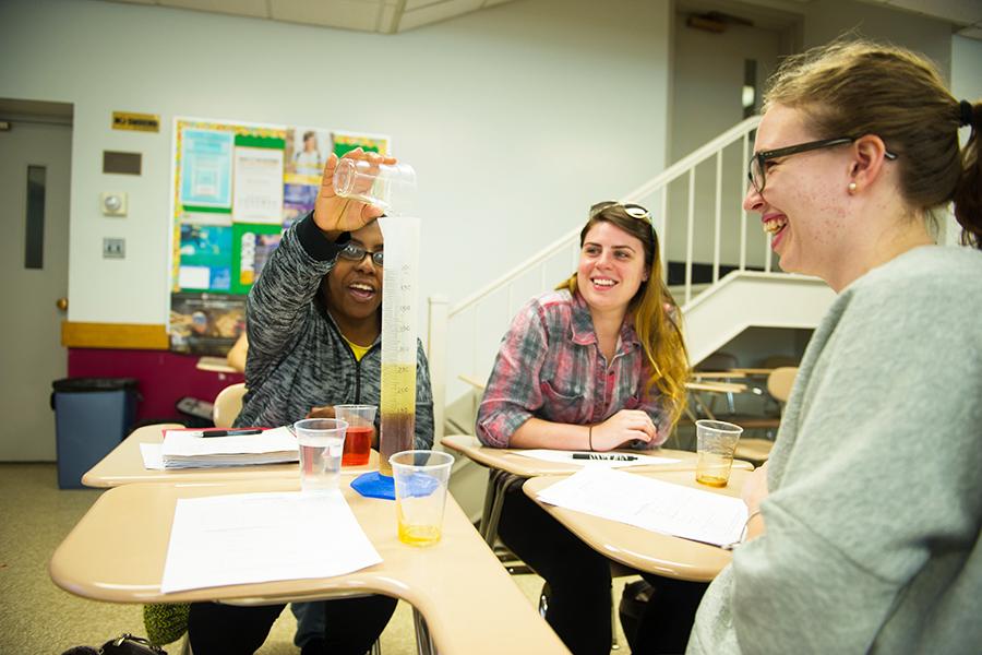 Science education majors perform a chemistry experiment and smile.