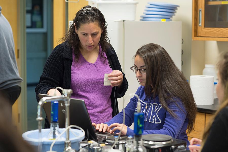 A biology professor helps a student use biology equipment.