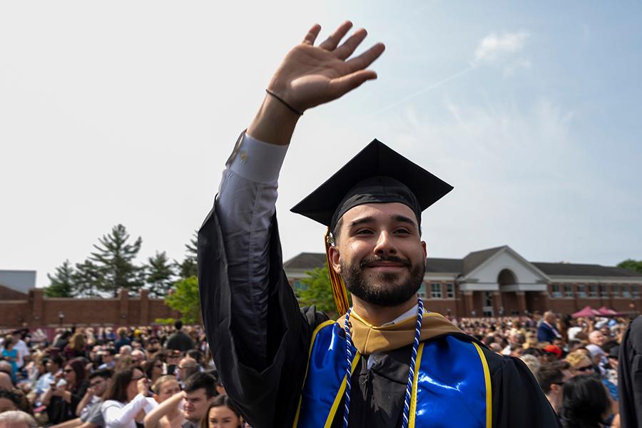 A graduate waves at the 2023 Commencement ceremony.