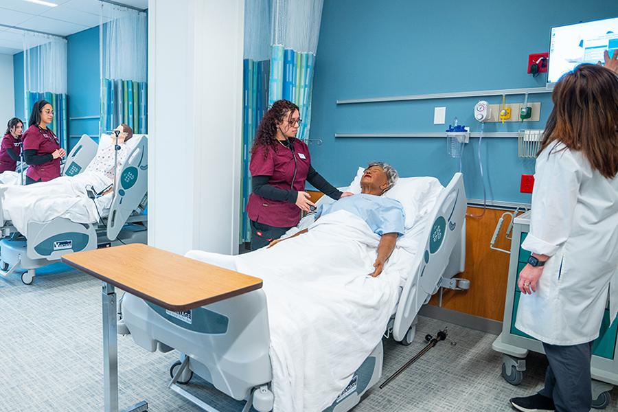 Three accelerated nursing students work in the simulation lab.