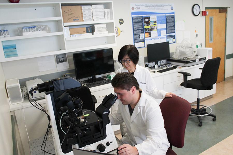Dr. Lee helps a student use the micropscope in her lab.