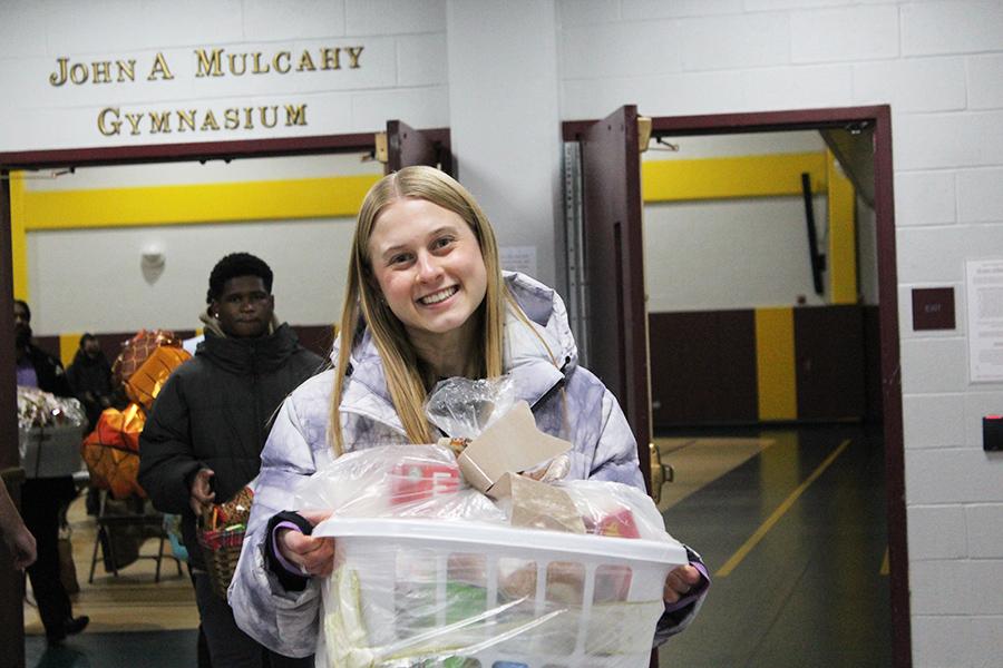 Annika holds a Thanksgiving Basket and smiles.