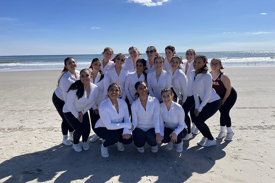 The cheer team gather round for a photo on a beach in Florida.