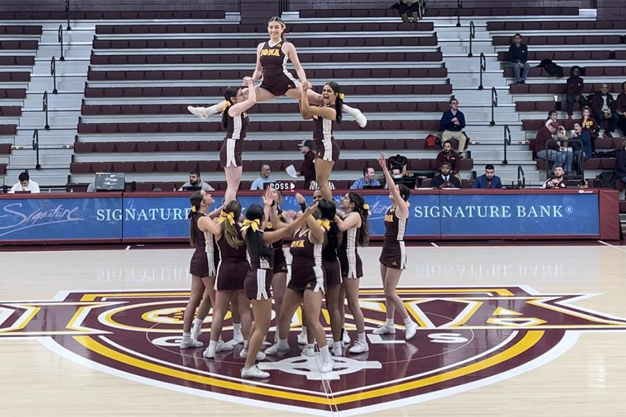 The cheer team make a pyramid and a member does a split at the top.