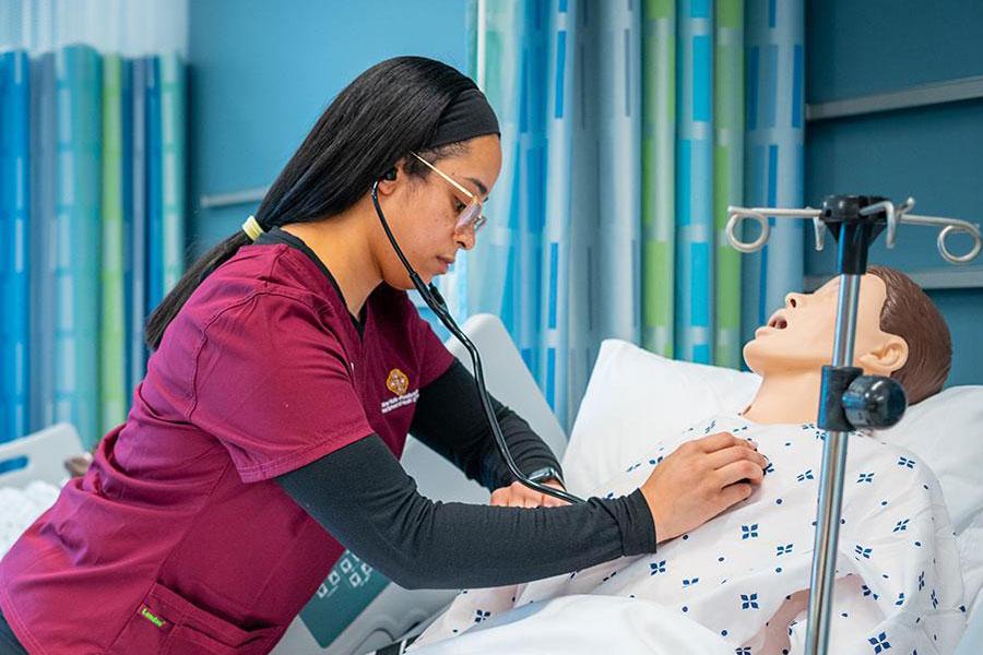 Three nurses in the simulation lab work with mannequins - 900x600