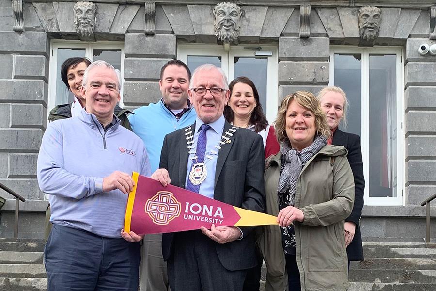 Leadership from Iona and Westport hold an Iona pennant.