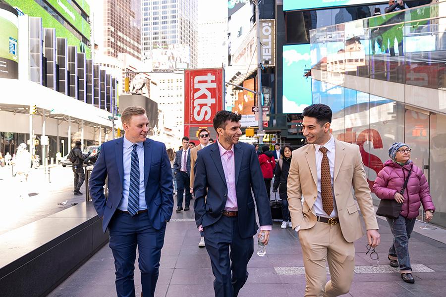 Iona students in suits walk through Times Square.