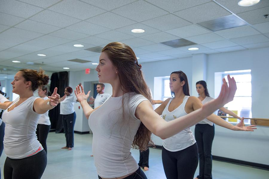 Students in a dance class spread their arms.