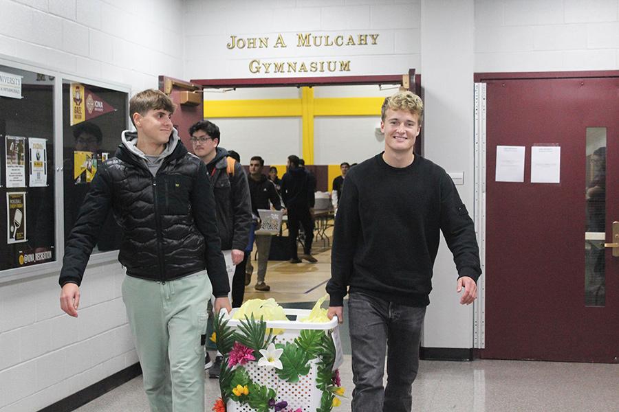 Two athletes carry Thanksgiving baskets to the vans.