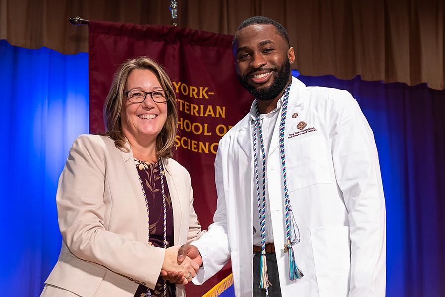 A nursing student and an adminstrator shake hands at the pinning ceremony.