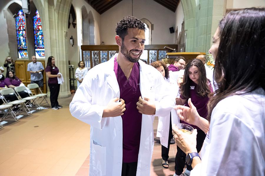 A student smiles at an Iona whitecoat ceremony.