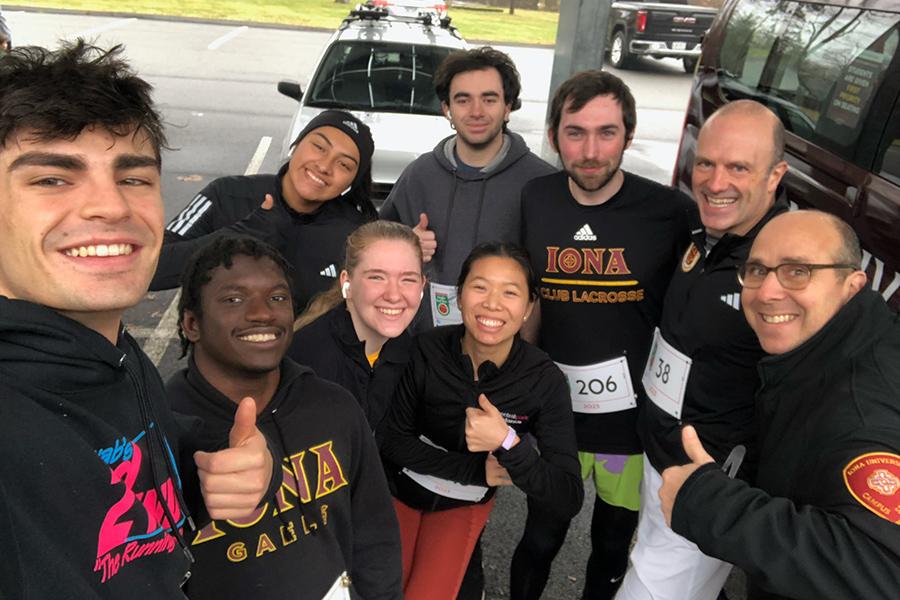 The co-ed running team giving a thumbs up and smiling.