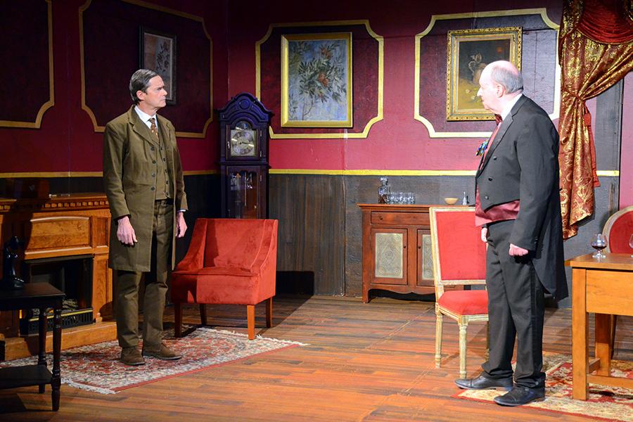 Two characters in An Inspector Calls stare at each other seriously and argue.