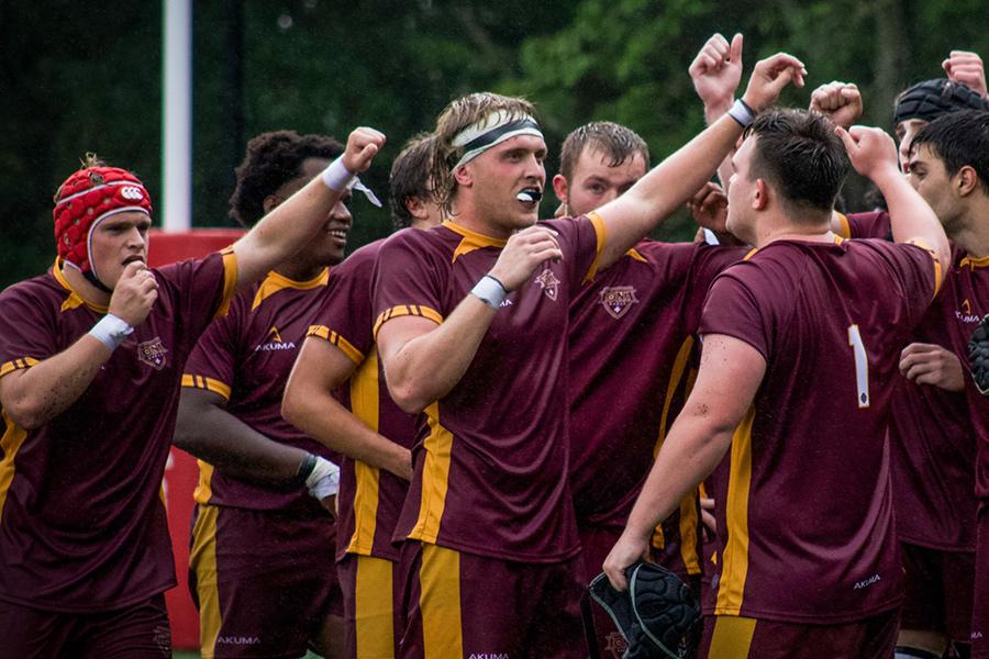 The rugby team raises their arms in victory.