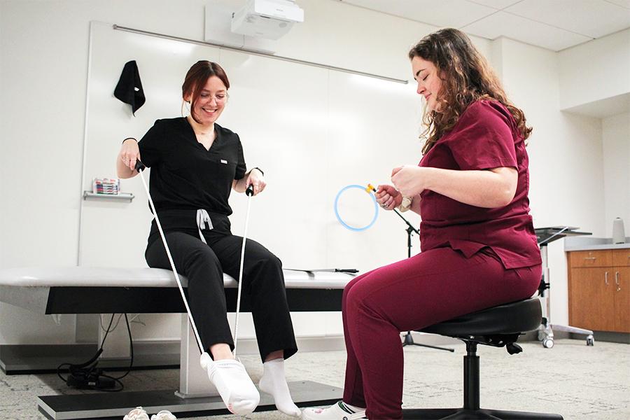 OT students practice putting on a shoe with a shoe strap.