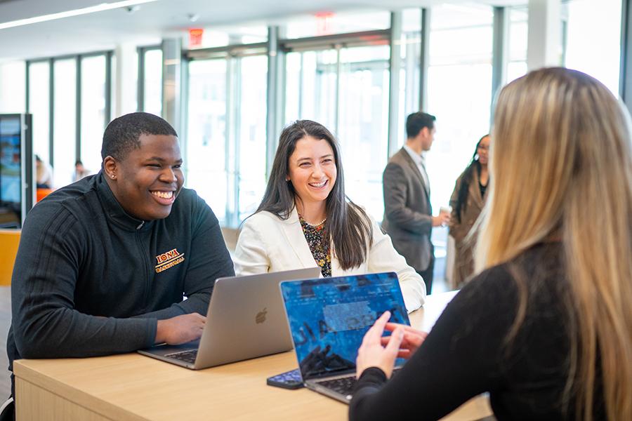 Three students work together and smile in the atrium in LSB.