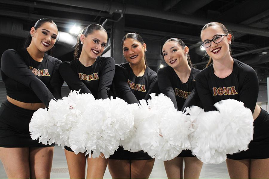 Five members of the dance team smile with white pom-poms.