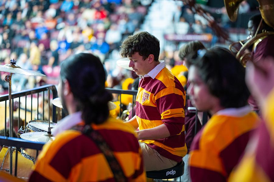 The drummer in the pep band plays at a game.