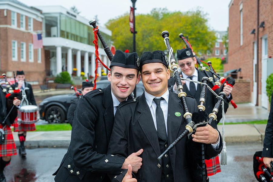 Two pipers smile on campus.