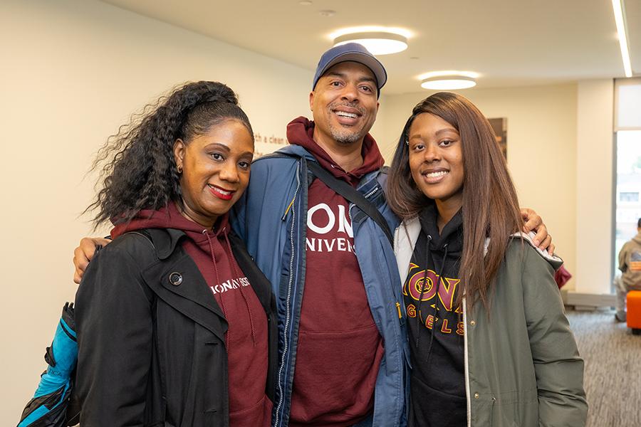 A student with her parents at homecoming weekend in Iona gear.