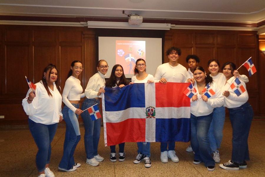 Bailando con Sazón members holding the flag from the Dominican Republic in Burke Lounge.