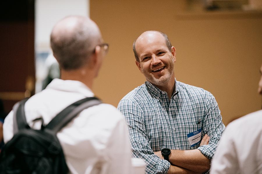 Attendees talk and smile at the conference. 