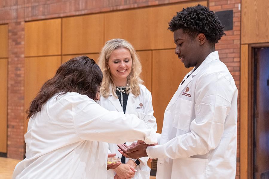 Two proffesors and a student at the white coat ceremony.