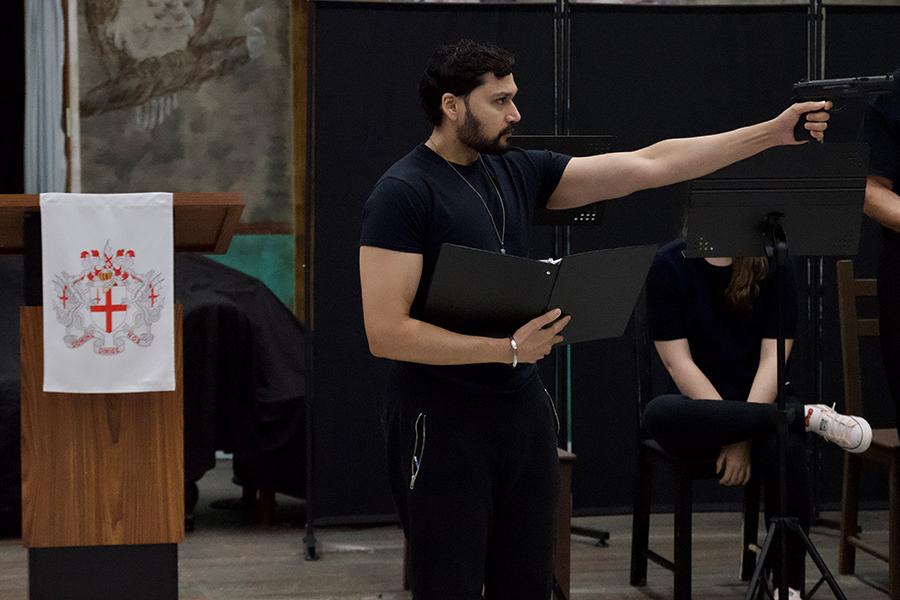 Male actor, during the performance of "Motherland," holding and pointing a weapon.