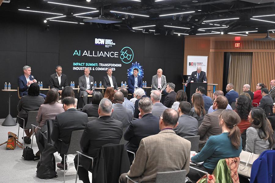 A large audience of over 50 professionals sits in a brightly lit auditorium during a presentation at the AI Alliance 360° Impact Summit.