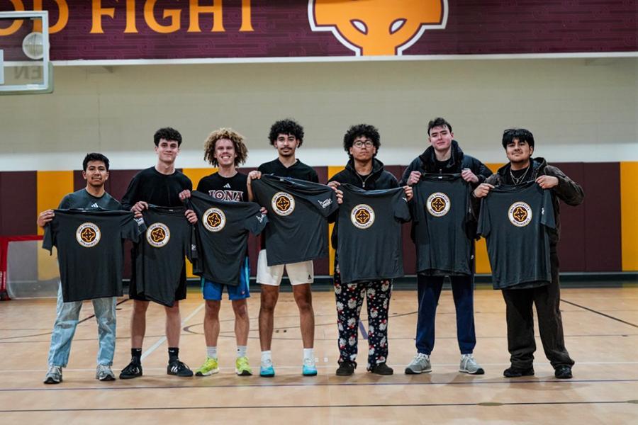 The intramural soccer team holds up their t-shirts.