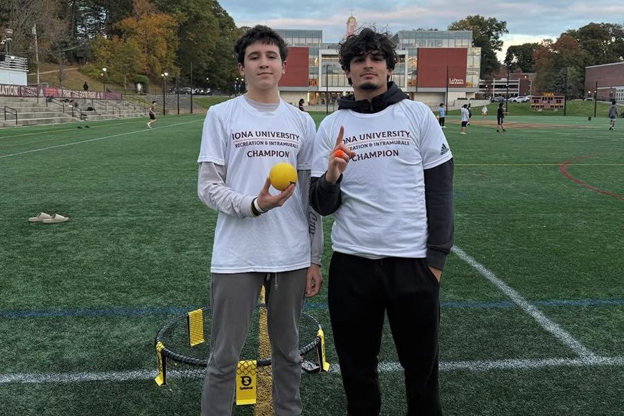 Two intramural spikeball players hold up their t-shirts on the Mazzella Field.