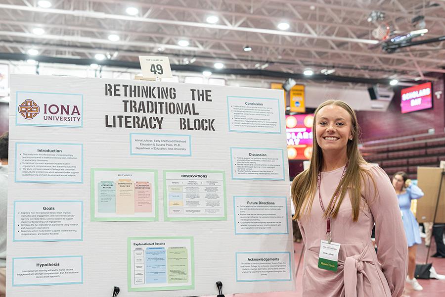 Student presenter smiling and standing next to her poster board at Iona Scholars Day.