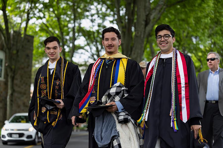 Three graduates smile and walk together.