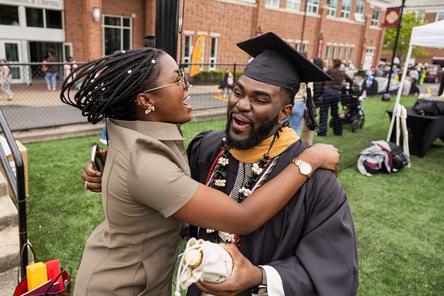 A graduate embraces his family member joyfully.