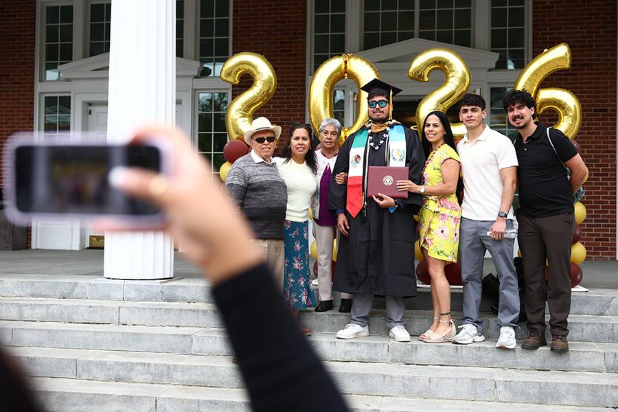 A person taking a picture of a family on the steps of Spellman.