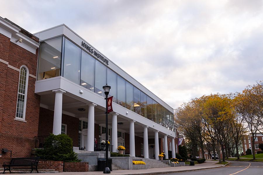 Exterior photo of the Hynes Institute building at the Iona University New Rochelle campus with students walking in front of the building during the day.