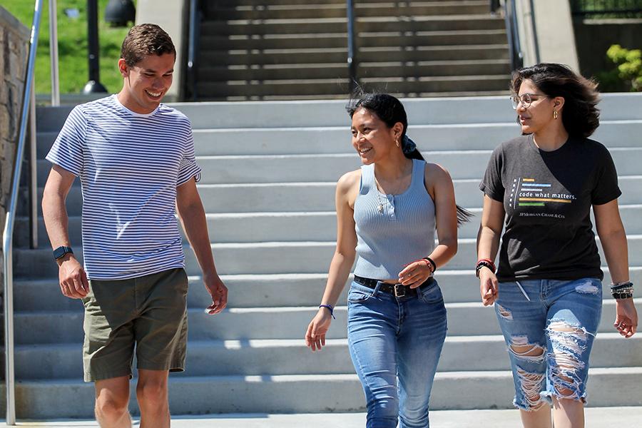 Three students walk on the steps near Murphy Green on a warm sunny day.