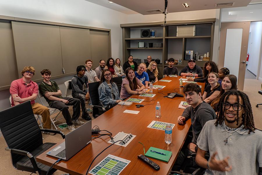 Faculty and students smiling while seated around a long conference table during their visit to Eos Energy Enterprises.