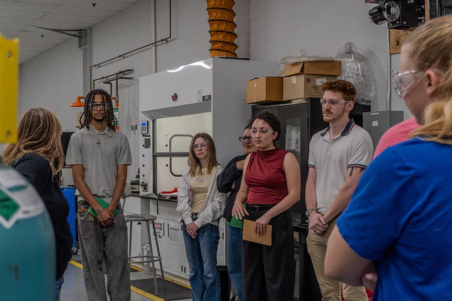 Iona University students wearing safety glasses while listening to a speaker inside a research and development laboratory at Eos Energy Enterprises.