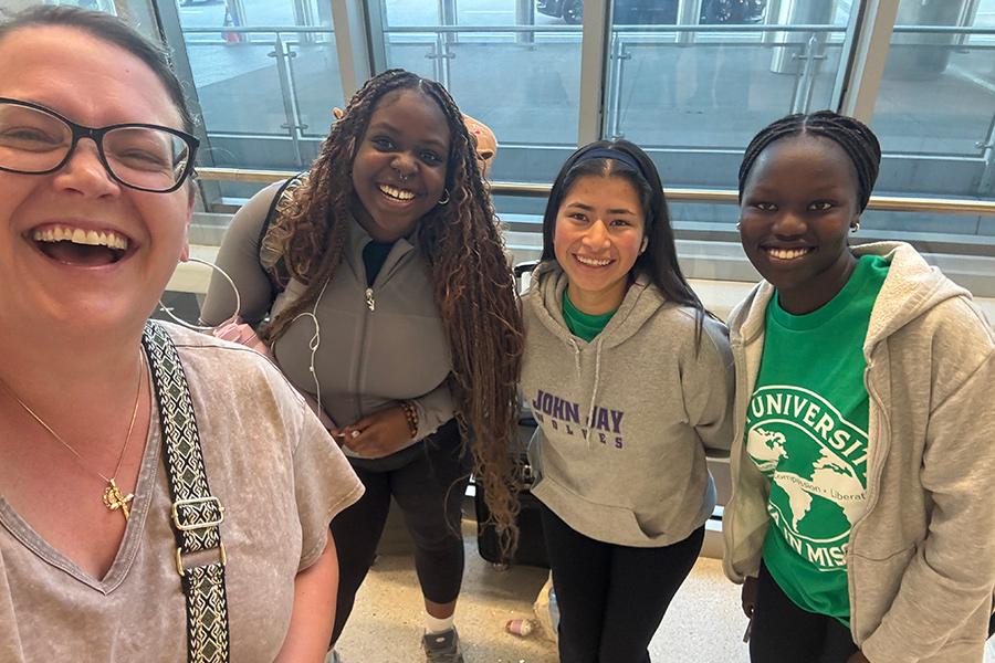 Four smiling participants gather together for a selfie before departing on an Iona University immersion trip.