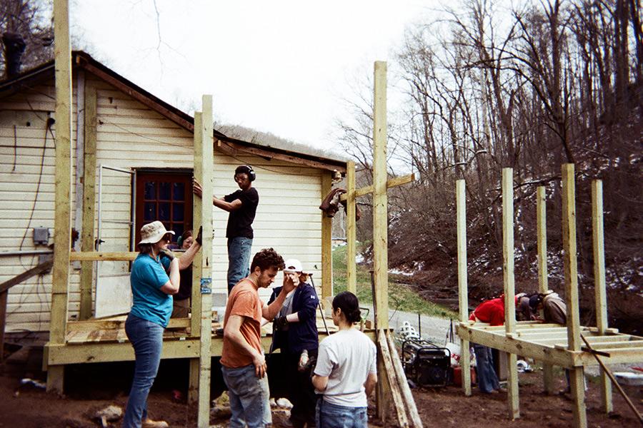 Students volunteering on an Iona University immersion trip work together to construct a wooden deck and building frame.