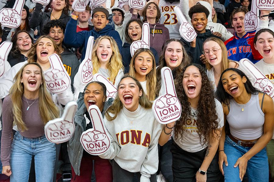 Iona students hold up "Iona University" foam fingers at a Gaels game.