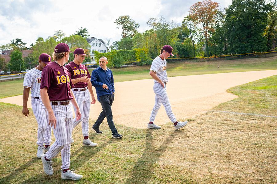 Matt Rizzetta walks on the baseball field with Iona players. 