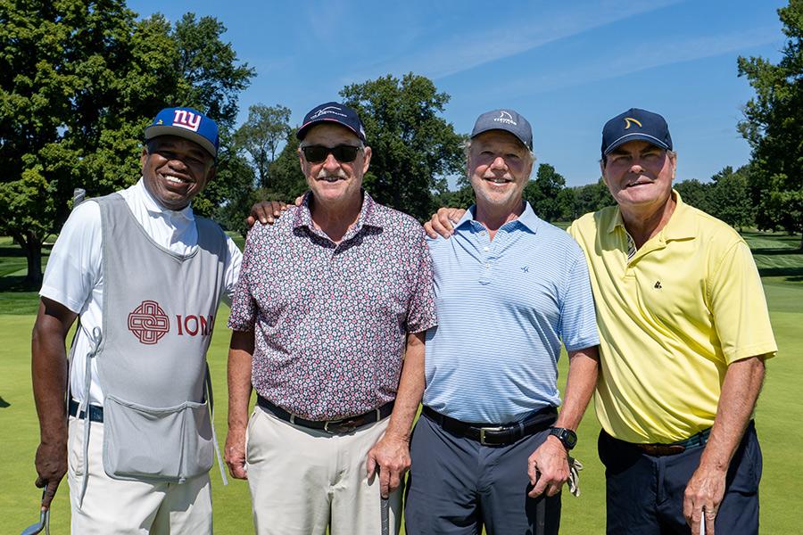 Four attendees smile on a sunny day on the course. 