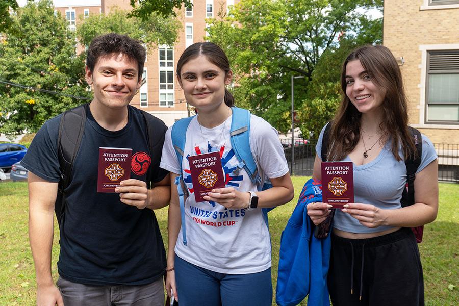 Three students hold their attention passports and smile.