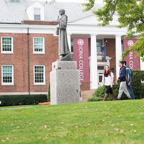 Iona students walk past the Columba statue in front of McSpedon Hall.