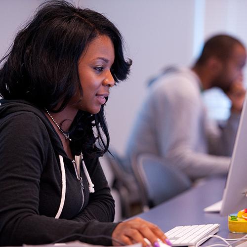 A student works on her online MBA at a desktop computer.